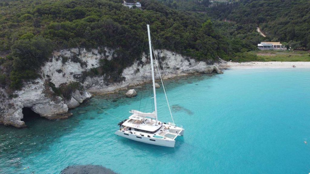 Katamaran Grace im türkisen Wasser an einer klippe in Griechenalnd.