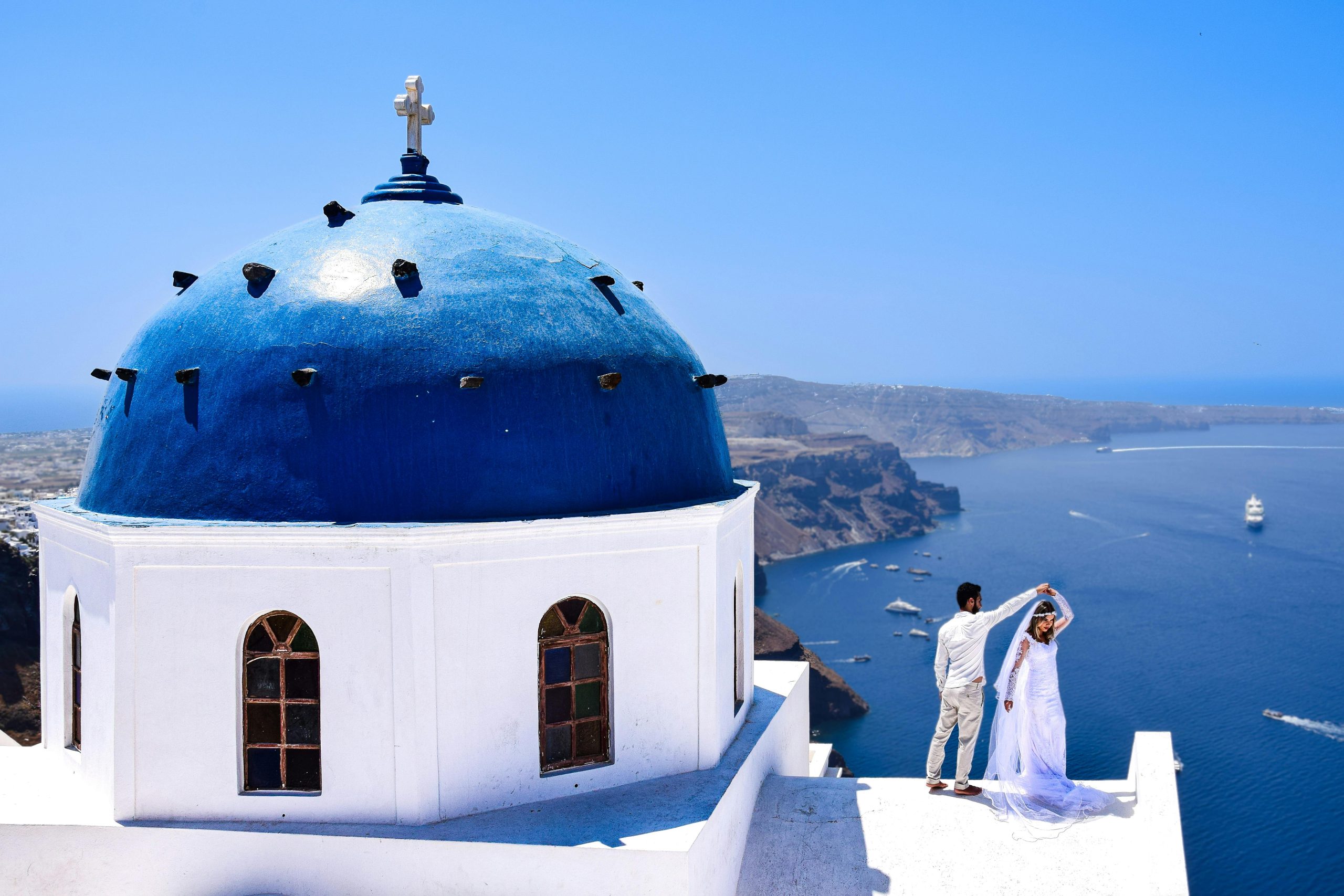 Ein Hochzeitspaar neben einer blauen Kupel in Santorini.